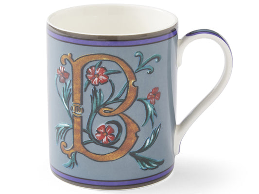 this stunning blue mug showcases a bronze letter 'B' intricately woven with lush green foliage and vibrant red flowers. The elegant artwork adorning the mug is gracefully framed by a border of purple and grey, reflecting its beauty on the cup handle
