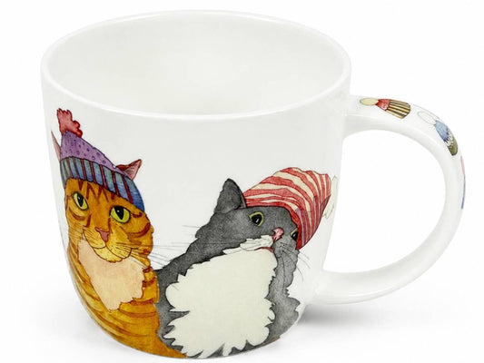 A white ceramic mug featuring a colorful illustration of two cats wearing knit hats, with a small cupcake motif on the handle.