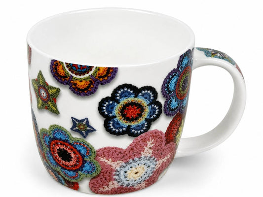A white ceramic mug decorated with colorful crocheted-style floral and star motifs, shown on a plain white background.