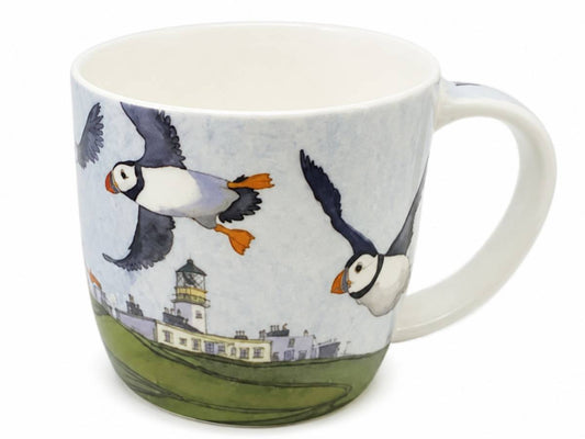 A white ceramic mug featuring a printed illustration of puffins flying above a lighthouse and grassy landscape, shown on a plain white background.