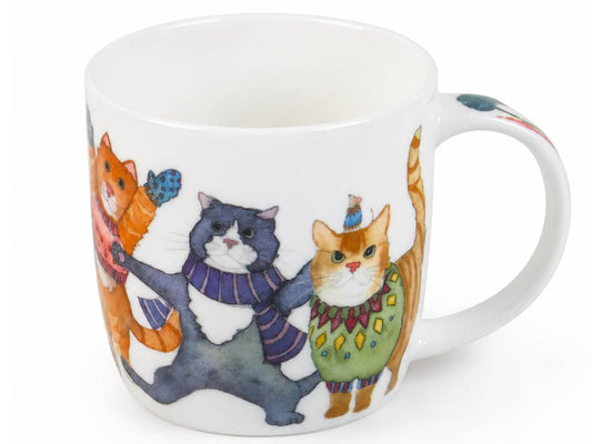 A white ceramic mug featuring a whimsical illustration of four cats dressed in colorful winter clothing, shown against a plain white background.