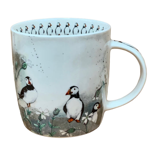 The Alex Clark mug features delightful puffins in their natural environment in its illustration. Adding to its charm, the mug includes illustrations of puffins around the inside rim and down the handle.
