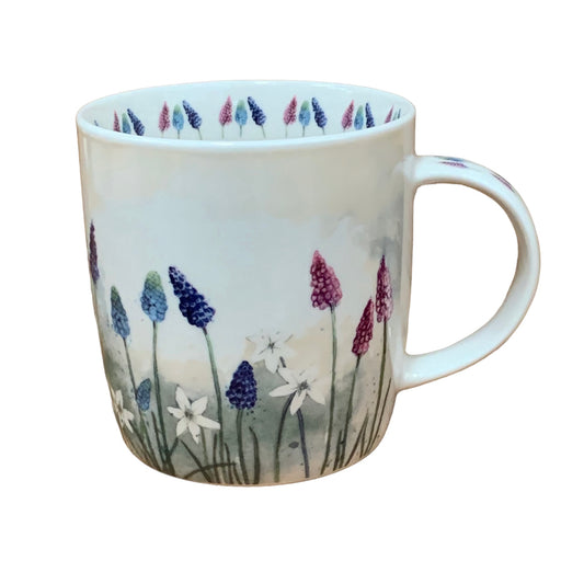 The Alex Clark mug showcases a delightful array of grape hyacinths flowers in various colors in its illustration. Adding to its charm, the mug includes illustrations of flowers around the inside rim and down the handle