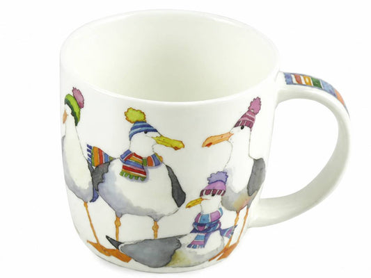 A white ceramic mug featuring a whimsical illustration of four seagulls wearing colorful knit hats and scarves, set against a plain white background.