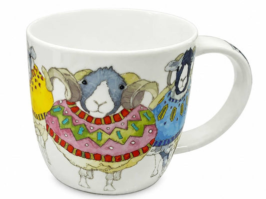 A white ceramic mug featuring a colorful illustration of three stylized sheep wearing patterned sweaters, shown on a plain white background.