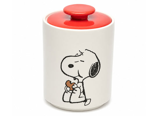 A white ceramic jar with a red lid and a black-and-white Snoopy illustration on the front, holding a small brown heart-shaped object.