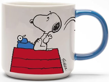 The mug showcases a depiction of Snoopy on his iconic red-roofed house, contemplating his writing with a typewriter, and playfully discarding a crumpled paper. On the reverse side, bold letters proudly announce 'Genius at Work