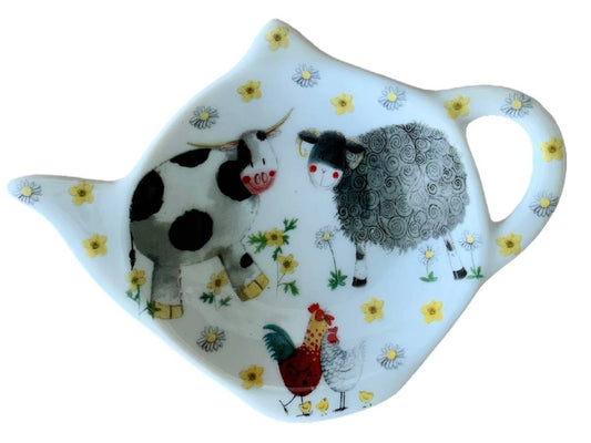 A white ceramic teapot-shaped dish featuring whimsical illustrations of a black-and-white cow, a gray sheep, a red rooster, and small yellow flowers, shown on a plain white background.