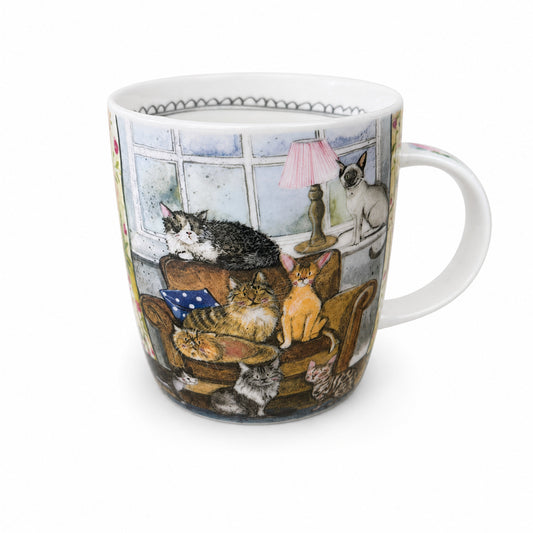 A white ceramic coffee mug featuring a detailed illustration of various cats lounging in a cozy living room setting, shown against a plain white background.