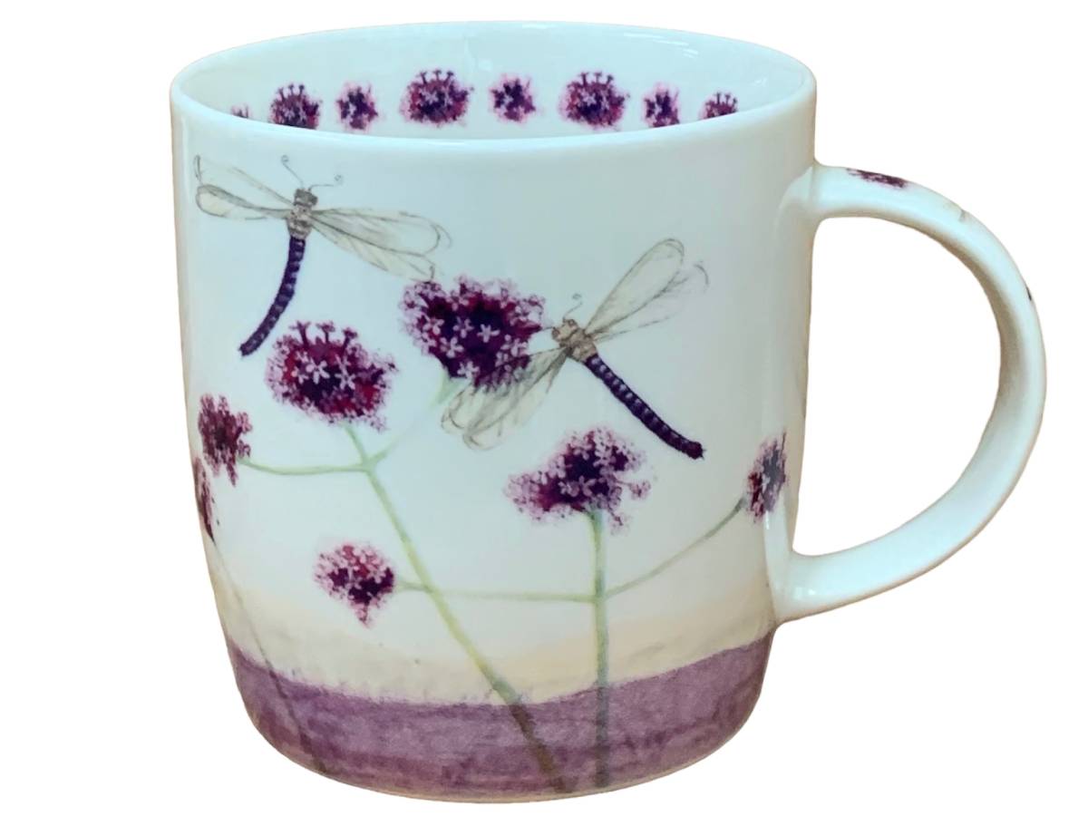 A white ceramic mug decorated with purple wildflower blossoms and dragonflies, featuring a solid purple band at the base.