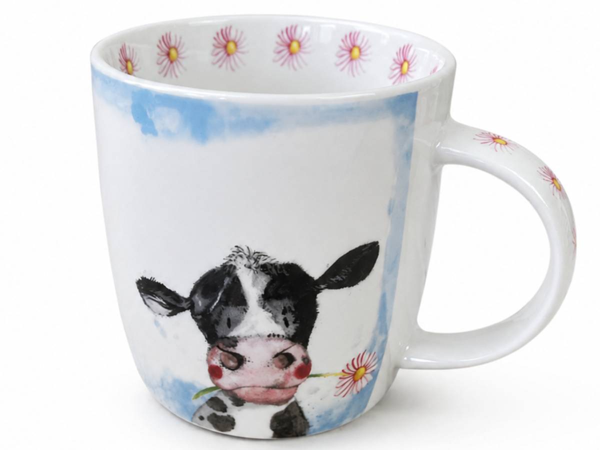 A white ceramic mug featuring a watercolor-style illustration of a black and white cow holding a pink flower, with a blue sky motif on the side and pink flowers around the rim.