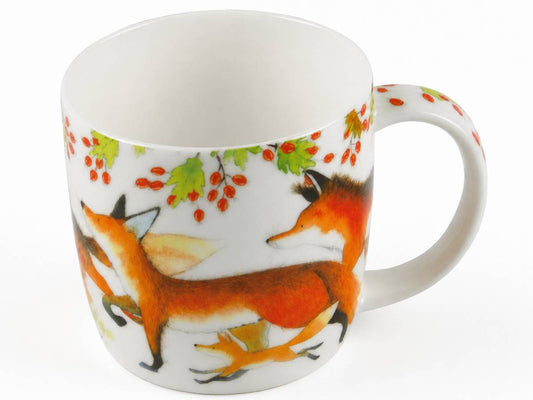 A white ceramic mug decorated with a whimsical illustration of foxes and autumn leaves, shown on a clean white background.