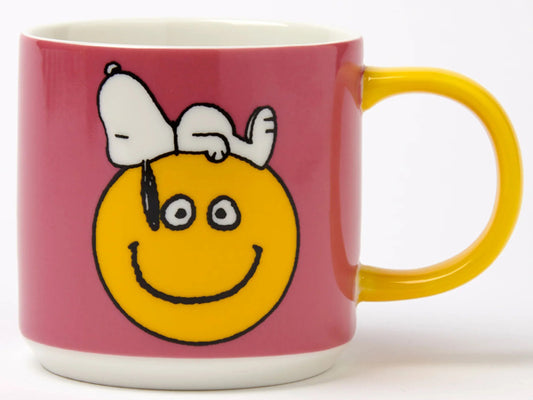 Magpie x Peanuts Have a Nice Day mug featuring Snoopy lying on a yellow smiley face, pink mug with yellow handle