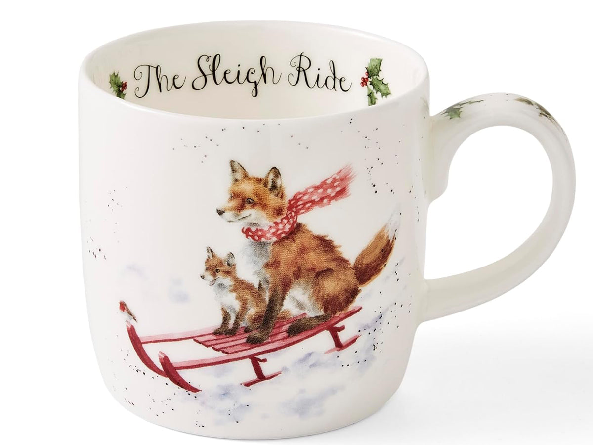 A white ceramic mug featuring a watercolor illustration of an adult fox and a small fox in a red sled, with the text 'The Sleigh Ride' printed inside the mug.