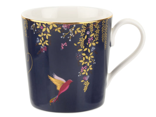 In the Sara Miller London Chelsea Mug in Navy, a hummingbird gracefully feeds off trailing blooms, depicting a scene of natural beauty. Known for its fusion of exotic birds and vibrant color palettes